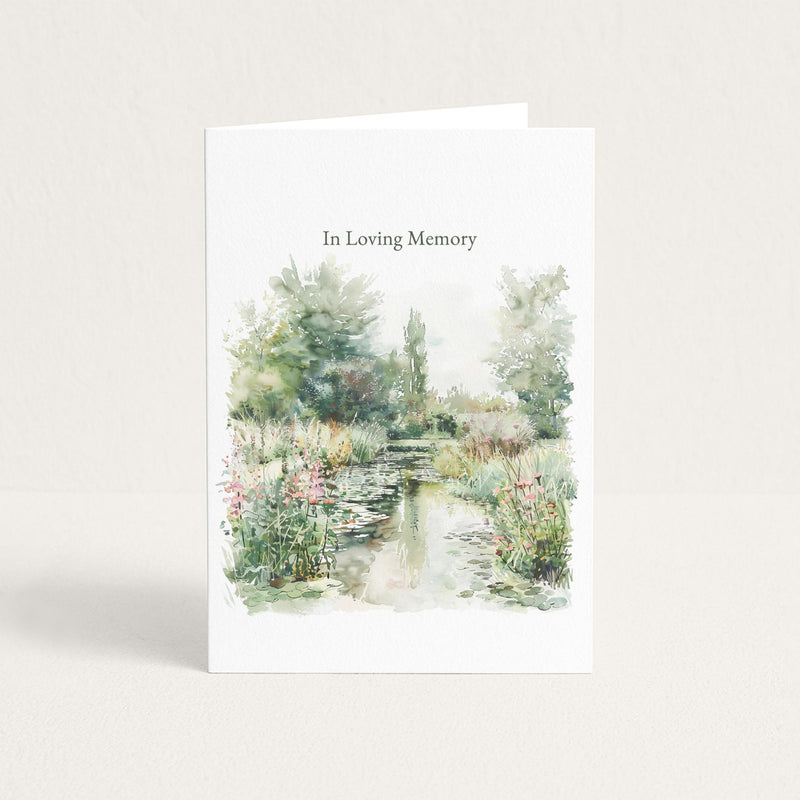 Sympathy card featuring a soft watercolor garden pond with flowers and trees beneath the words “In Loving Memory.”