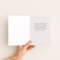Open sympathy card held in hand, showing a printed message about love, memories, comfort, and peace after loss.