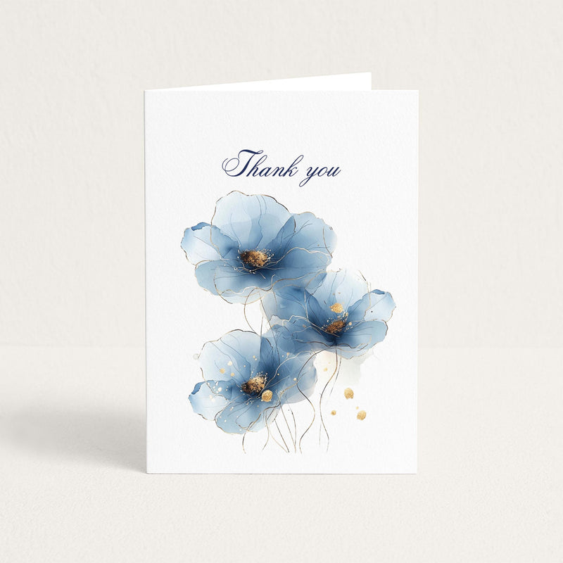 Thank-you greeting card featuring three soft blue watercolor flowers with delicate gold accents on white textured paper.