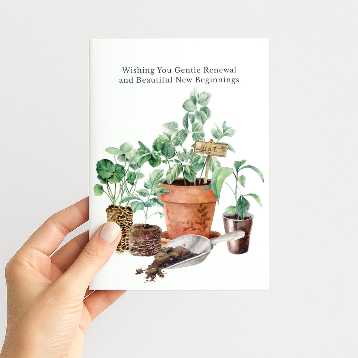 Hand holding an encouragement card featuring watercolor seedlings, terracotta pots, herbs, and gardening tools.