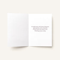 Open thinking-of-you card showing the printed message about cherry blossoms, quiet gardens, and how much the recipient means.