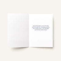 Open thinking-of-you greeting card showing a printed message about remaining close across the miles and through life’s changing seasons.