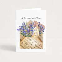 A Letter for You thinking-of-you card featuring lavender flowers, vintage postcards, and a sheet-music envelope.