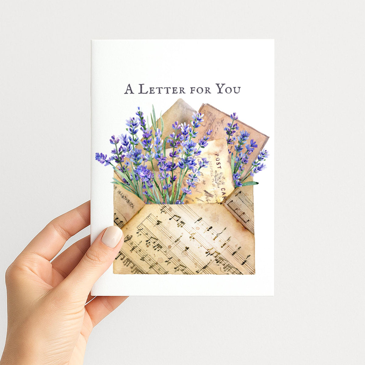 Hand holding A Letter for You card featuring lavender, vintage correspondence, and musical notation.
