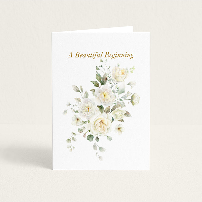 A Beautiful Beginning wedding card featuring soft white watercolor roses and greenery on textured white paper.