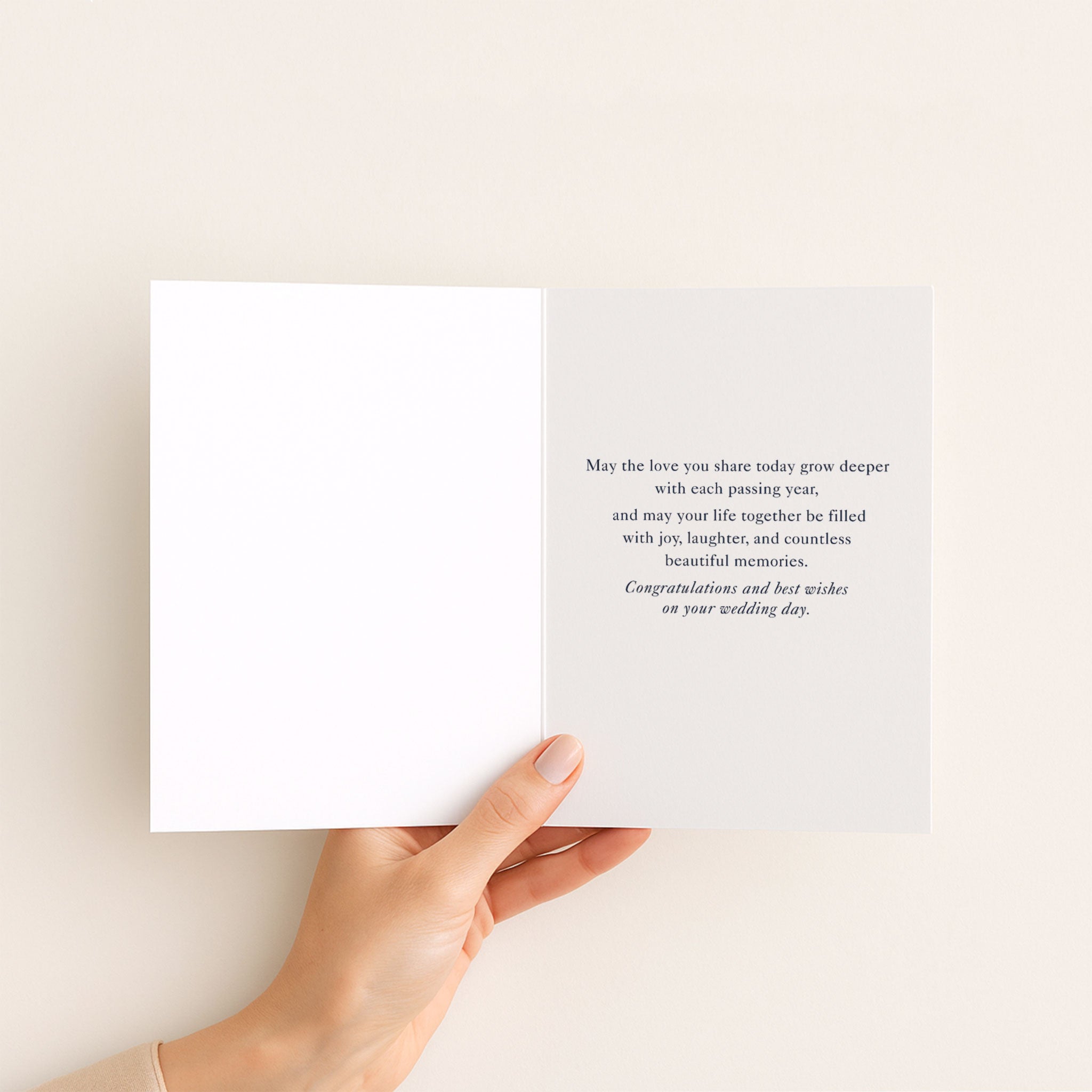 Open wedding card held by hand, showing a message of love, joy, laughter, and beautiful memories.