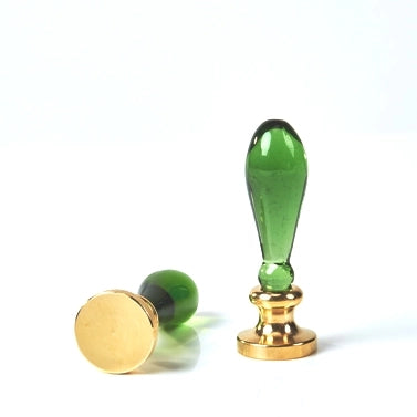 Green glass stamp with gold base on a white background