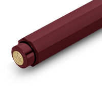 A close-up of a metallic burgundy cylindrical product, showing a hexagonal body and a circular gold-toned cap with embossed branding, set against a plain white background.