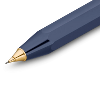 A close-up of a faceted navy blue pen tip with a polished gold metal cone and a fine silver writing point, shown on a clean white background.