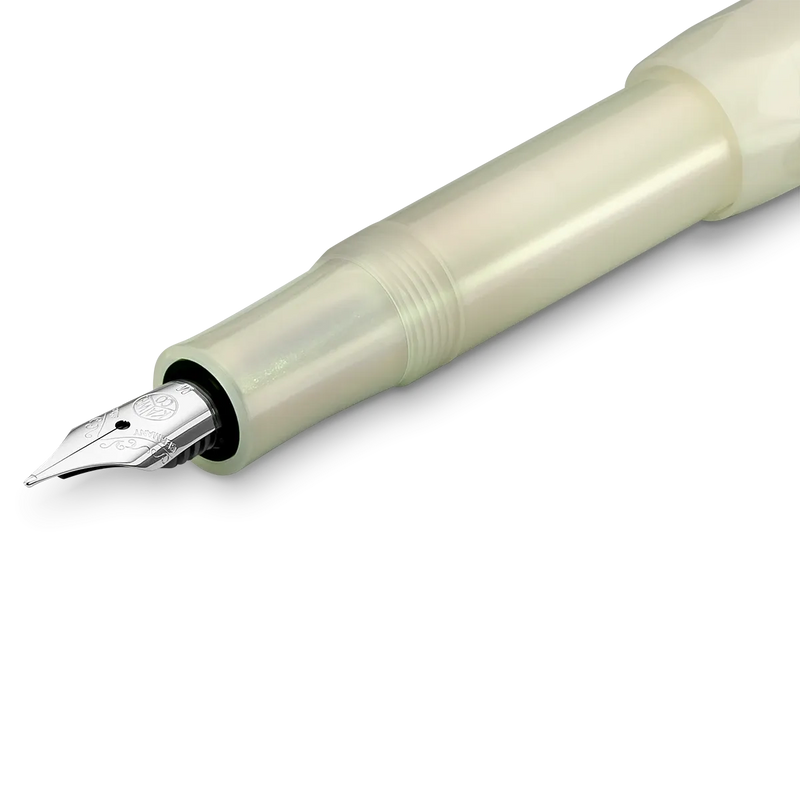 A close-up of a fountain pen nib and upper barrel section, showing a polished silver nib inside a translucent pale green or ivory-colored protective sleeve on a white background.