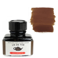 A bottle of Herbin Lie de Thé ink with a black cap and a white label, shown next to a brown ink swatch on a white background.