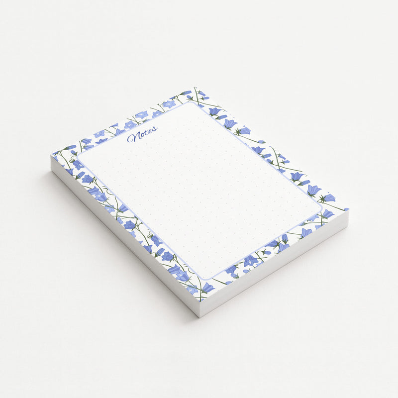 Bluebell Garden memo pad shown at an angle with a blue bellflower border, script Notes heading, and subtly dotted writing area.