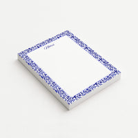 Indigo Botanica memo pad shown at an angle with a deep blue botanical border, lavender rounded frame, and subtly dotted writing area.