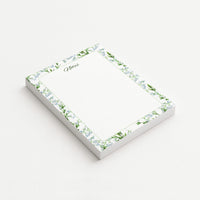 Lily of the Valley memo pad shown at an angle with pale blue bell-shaped flowers, green leaves, a script Notes heading, and subtly dotted writing area.