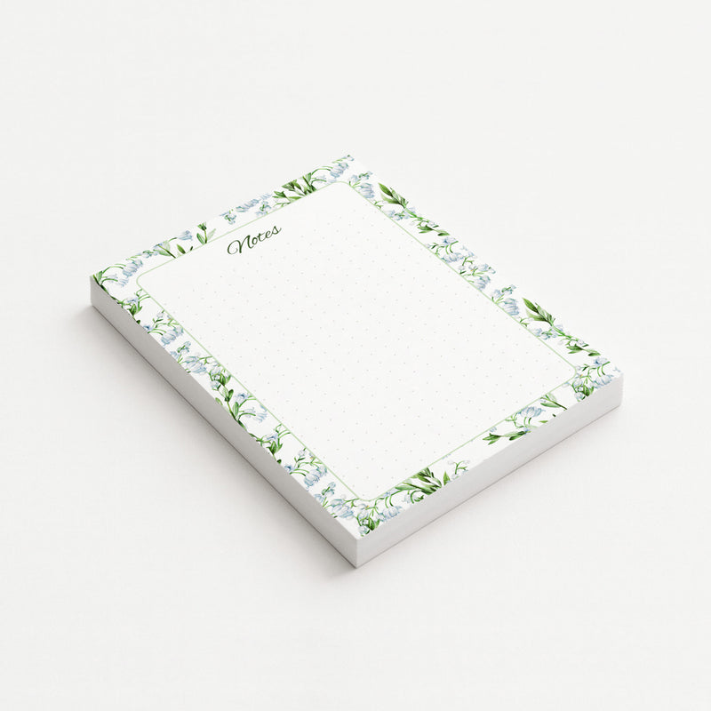 Lily of the Valley memo pad shown at an angle with pale blue bell-shaped flowers, green leaves, a script Notes heading, and subtly dotted writing area.
