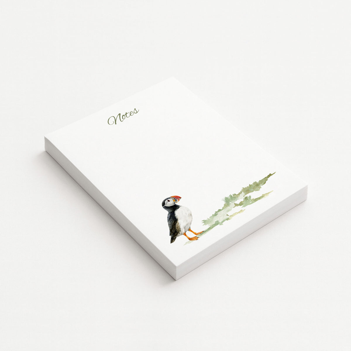 White 4.25" × 5.5" memo pad with olive “Notes” lettering and a watercolor Atlantic puffin beside soft green coastal grasses.