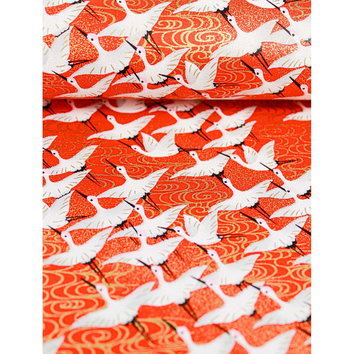 Close-up of hand silk-screen printed Chiyogami paper showing white cranes, black details, and warm gold wave motifs on red.