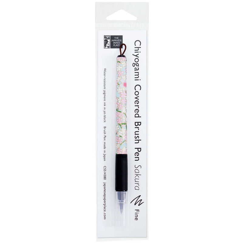 A Sakura fine brush pen wrapped in decorative Japanese Chiyogami paper with black rubber grips and capped felt tips.